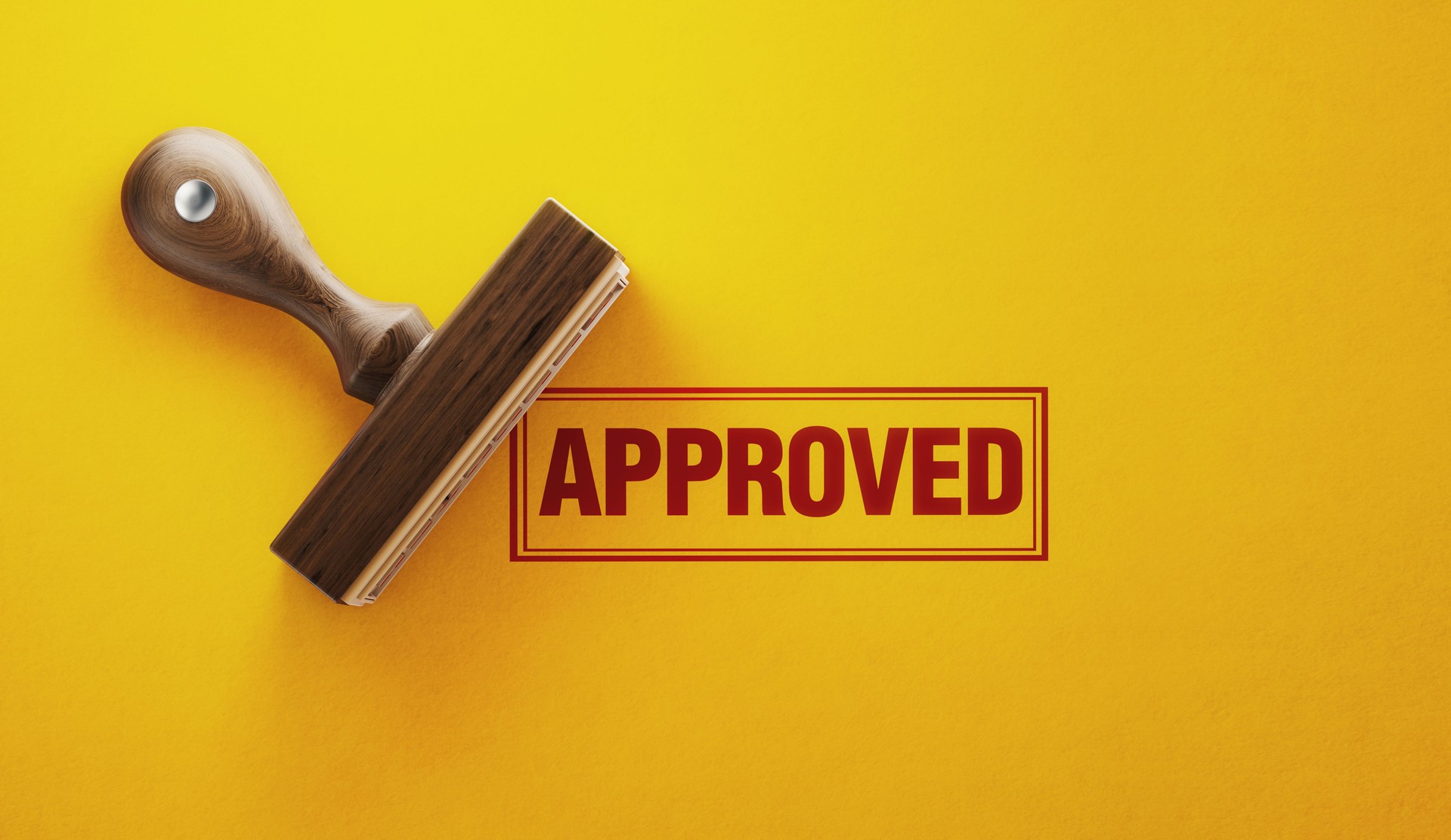 Rubber stamp with the word APPROVED on a bright yellow background, symbolizing nonprofit grant readiness and funding approval.