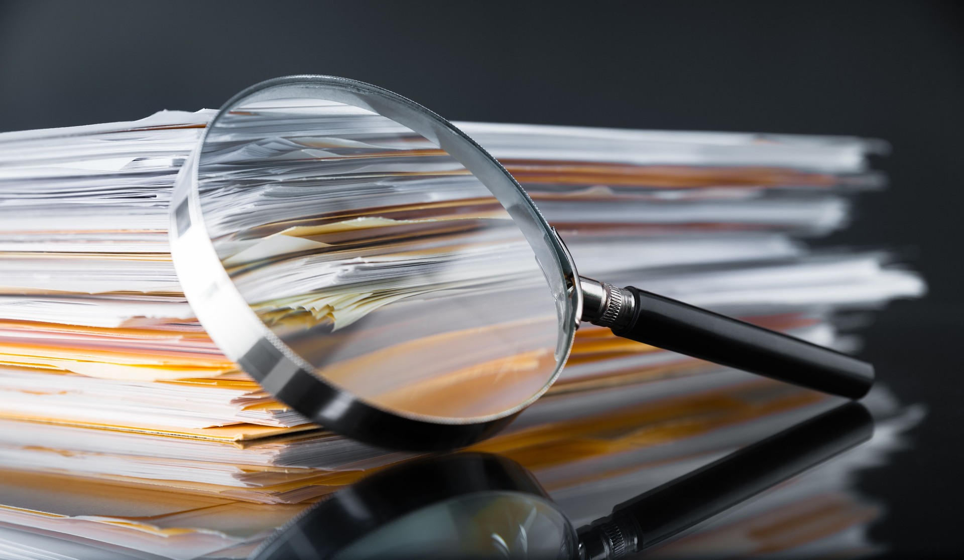 Magnifying glass focused on nonprofit paperwork to represent clarity and simplified compliance documentation