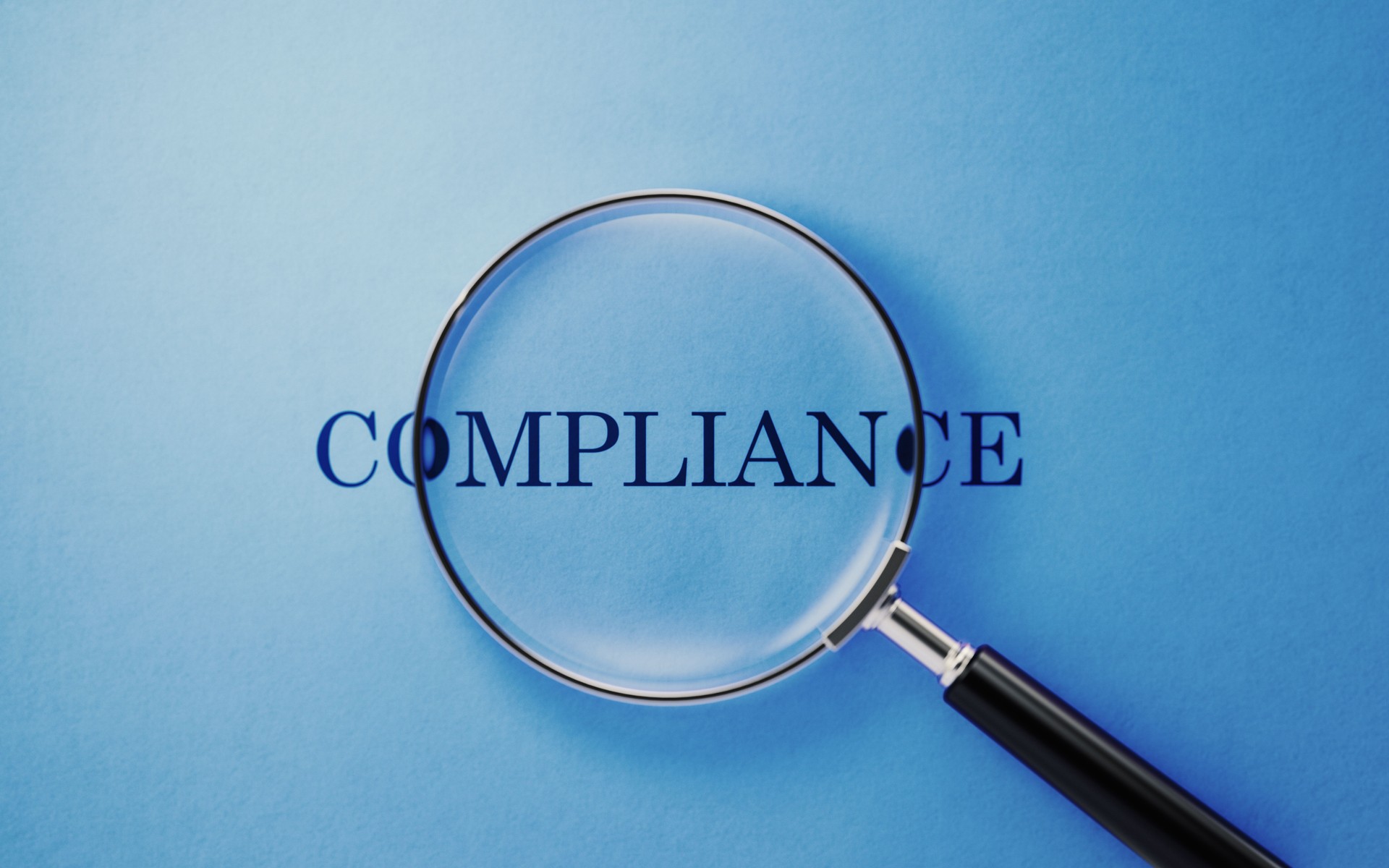Magnifying glass highlighting the word compliance on a blue background, representing nonprofit compliance review and legal due diligence