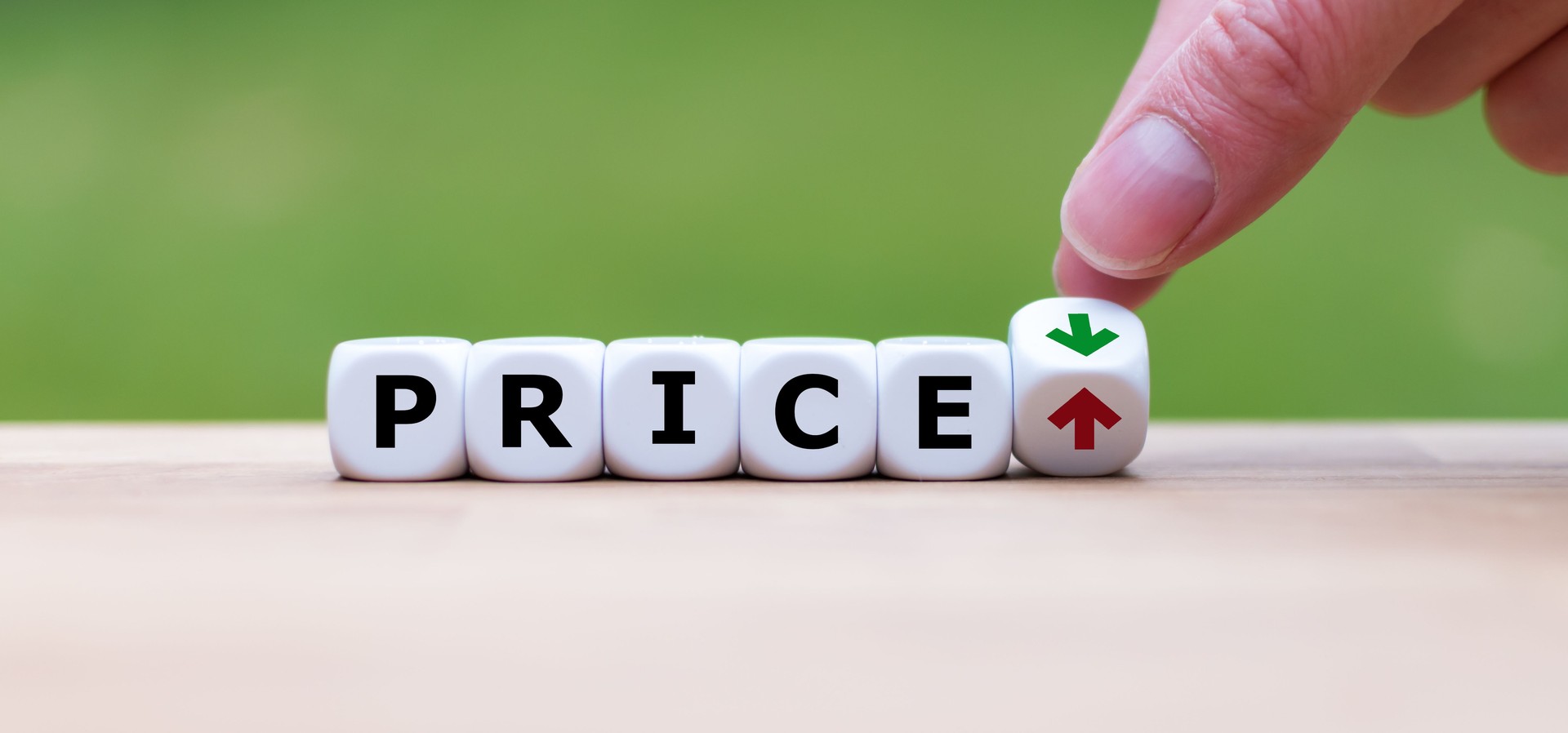 Hand adjusting price indicator dice with up and down arrows representing affordable nonprofit compliance services